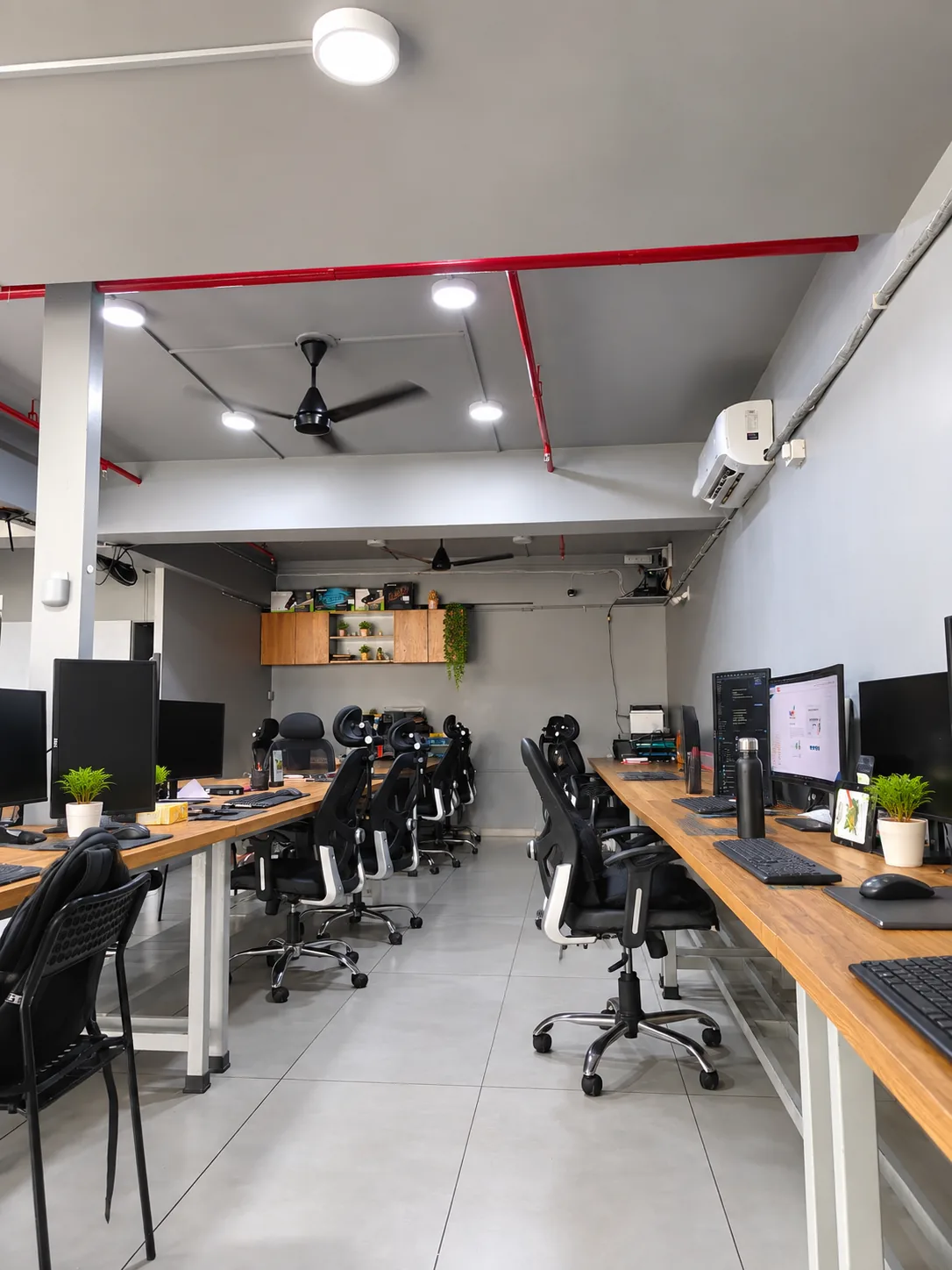 Desks and chairs seen across the new office floor beneath a ceiling fan.