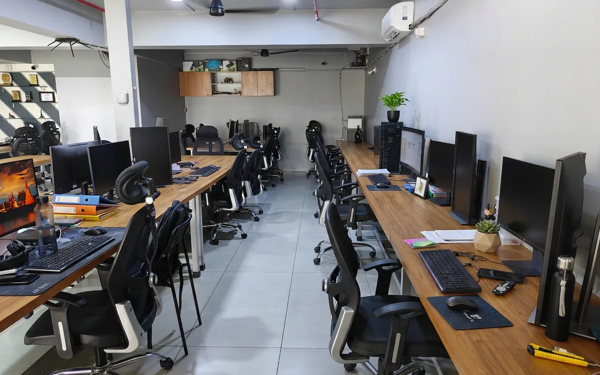 The far bench of the new office, monitors and chairs receding toward the wall.